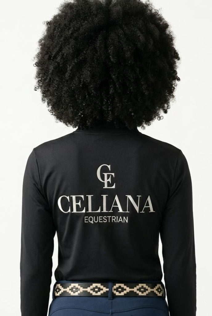Vista trasera del base layer de equitación negro de manga larga con logo CE y texto Celiana Equestrian estampado en la espalda, llevado por una amazona con cinturón étnico, fondo blanco