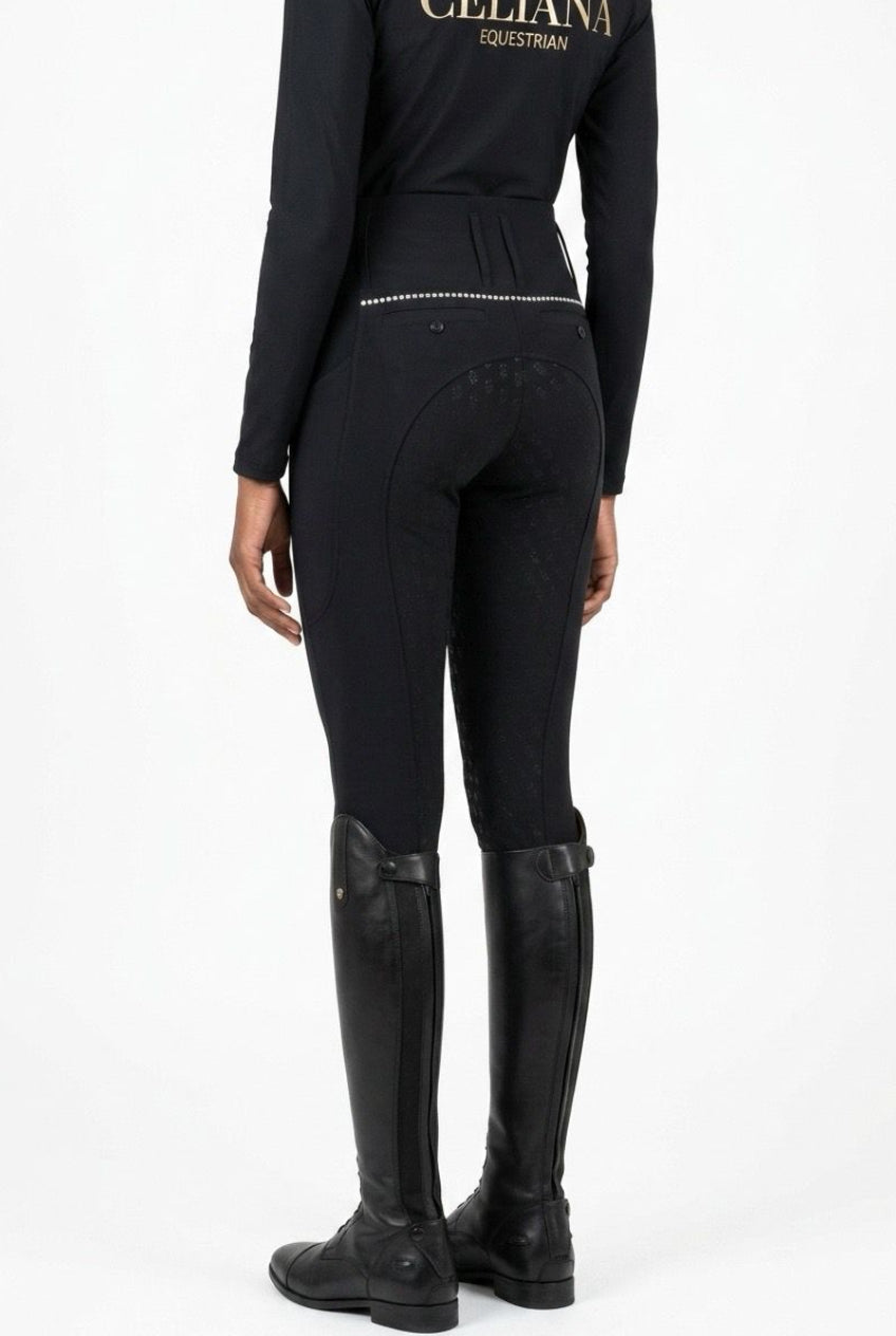 Vista trasera del pantalón de equitación negro ajustado con detalle de strass en la cintura, combinado con base layer negro Celiana Equestrian, llevado por una amazona con botas de campo negras, fondo blanco