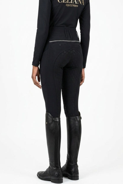 Vista trasera del pantalón de equitación negro ajustado con detalle de strass en la cintura, combinado con base layer negro Celiana Equestrian, llevado por una amazona con botas de campo negras, fondo blanco