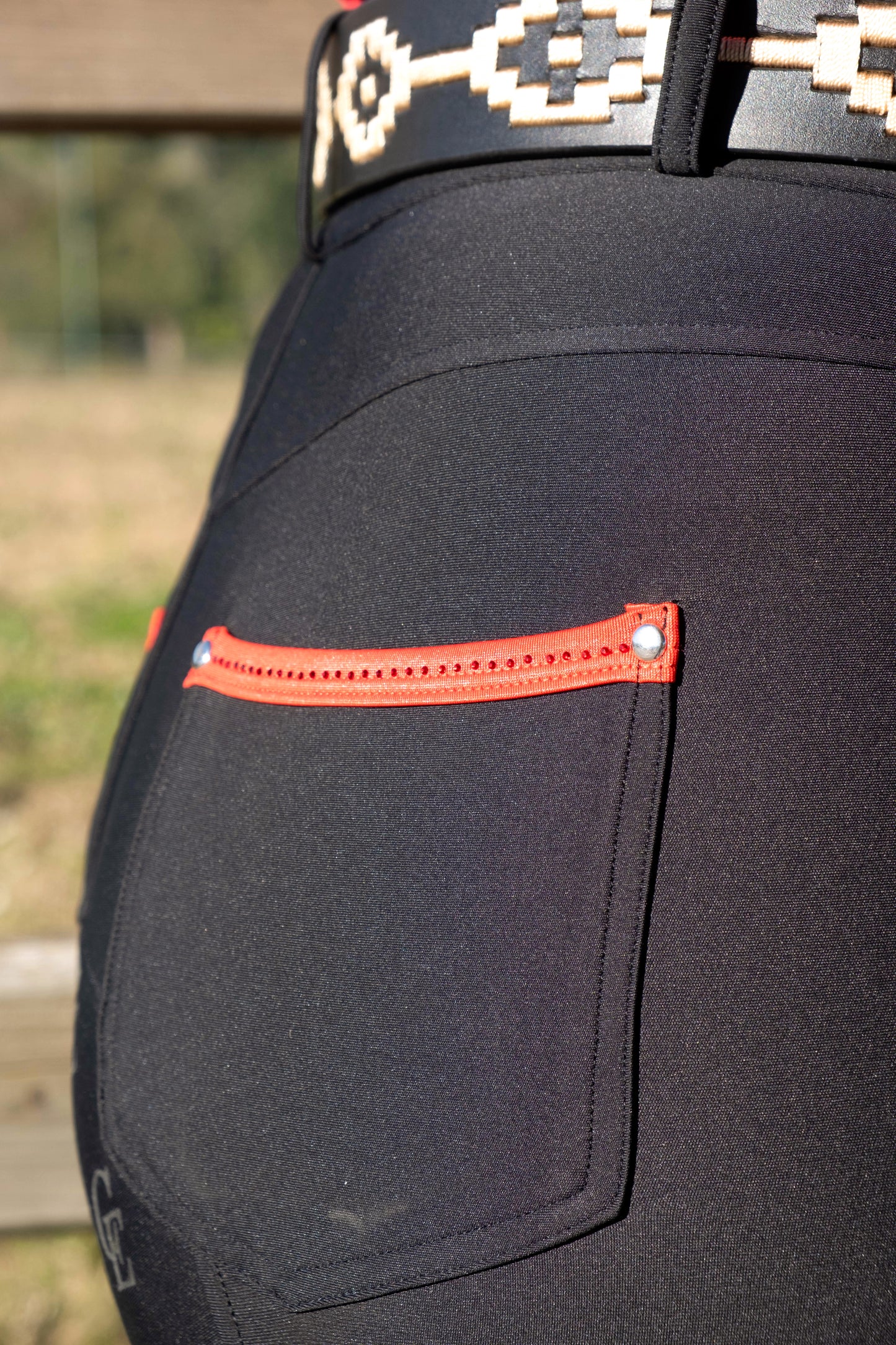 Detalle trasero pantalón de equitación mujer negro Celiana Equestrian bolsillo con cremallera roja
