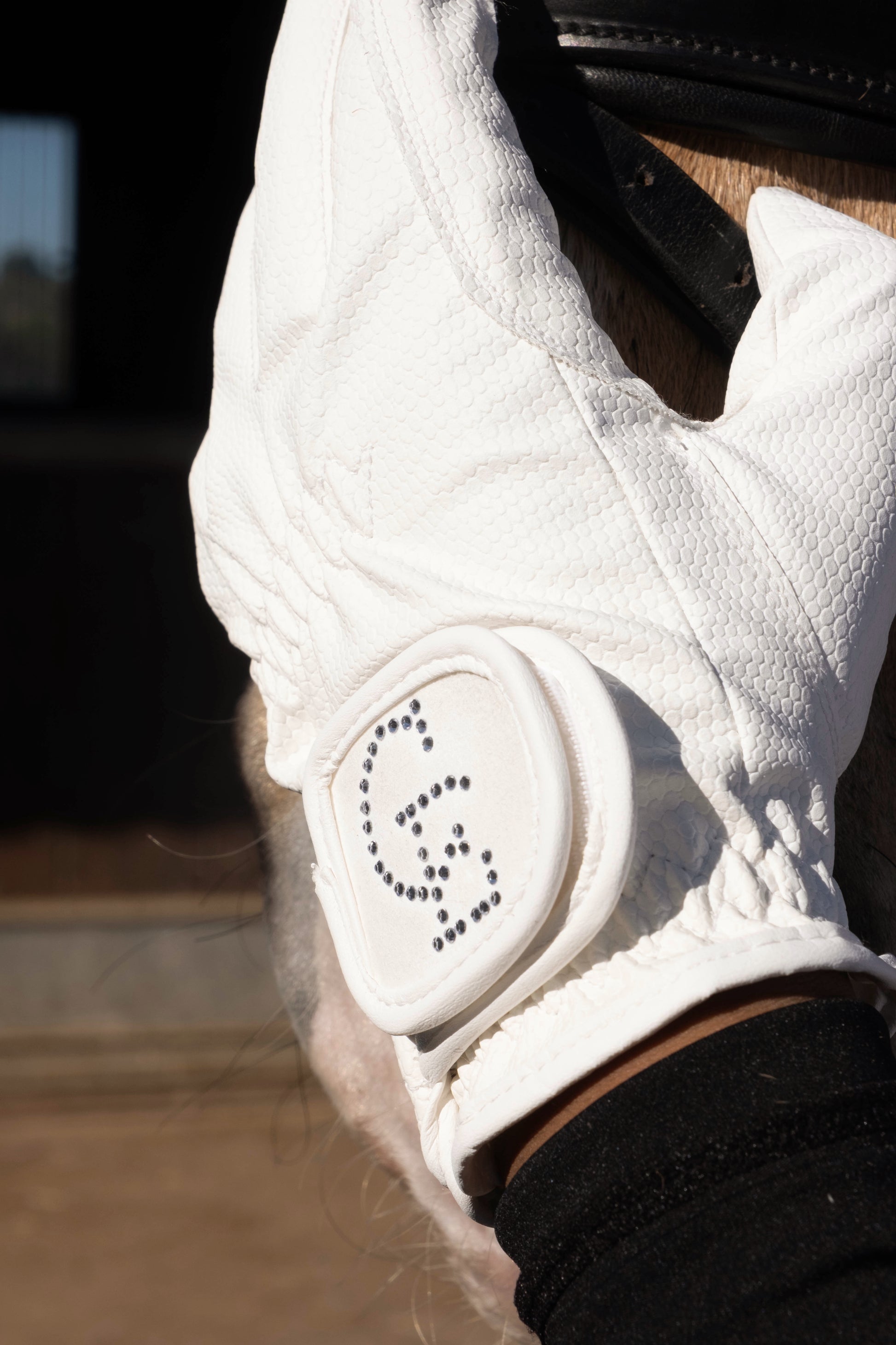 Detalle guante de equitación blanco Celiana Equestrian con logo en strass