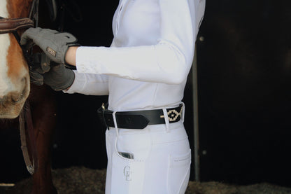 Cinturón ecuestre de cuero negro y beige puesto en amazona con breeches blancos – Celiana Equestrian