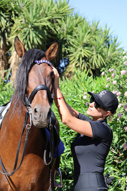 Amazona con gorra ecuestre negra Celiana Equestrian con logo CE preparando a su caballo