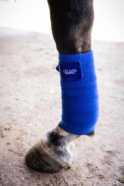 Detalle de una venda de trabajo azul Celiana Equestrian en la pata de un caballo, con etiqueta bordada con el logo